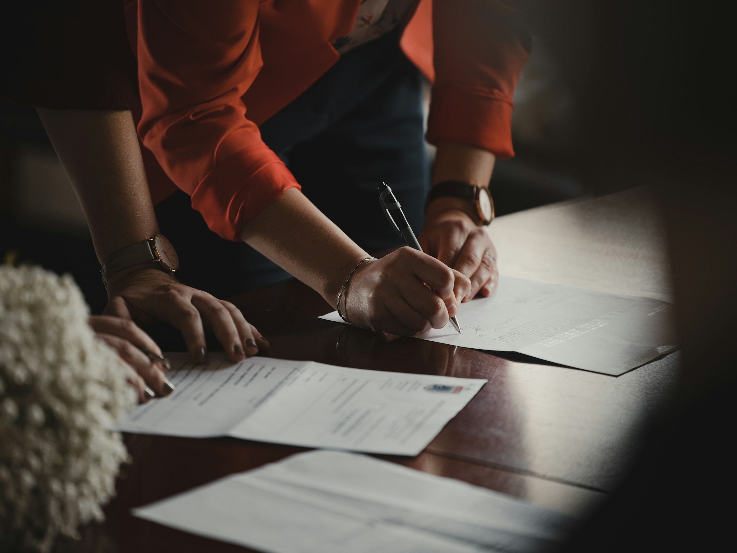 Two people signing documents together at a desk