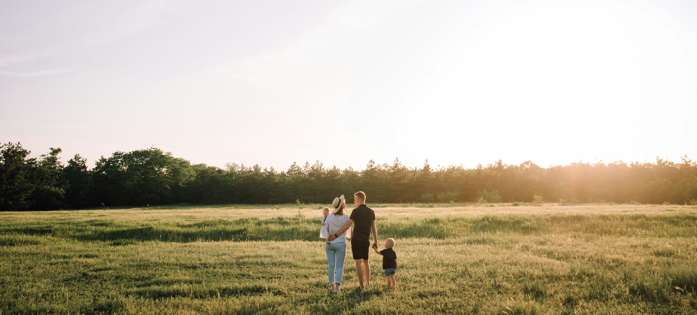 A family walking through a sunlit meadow at golden hour