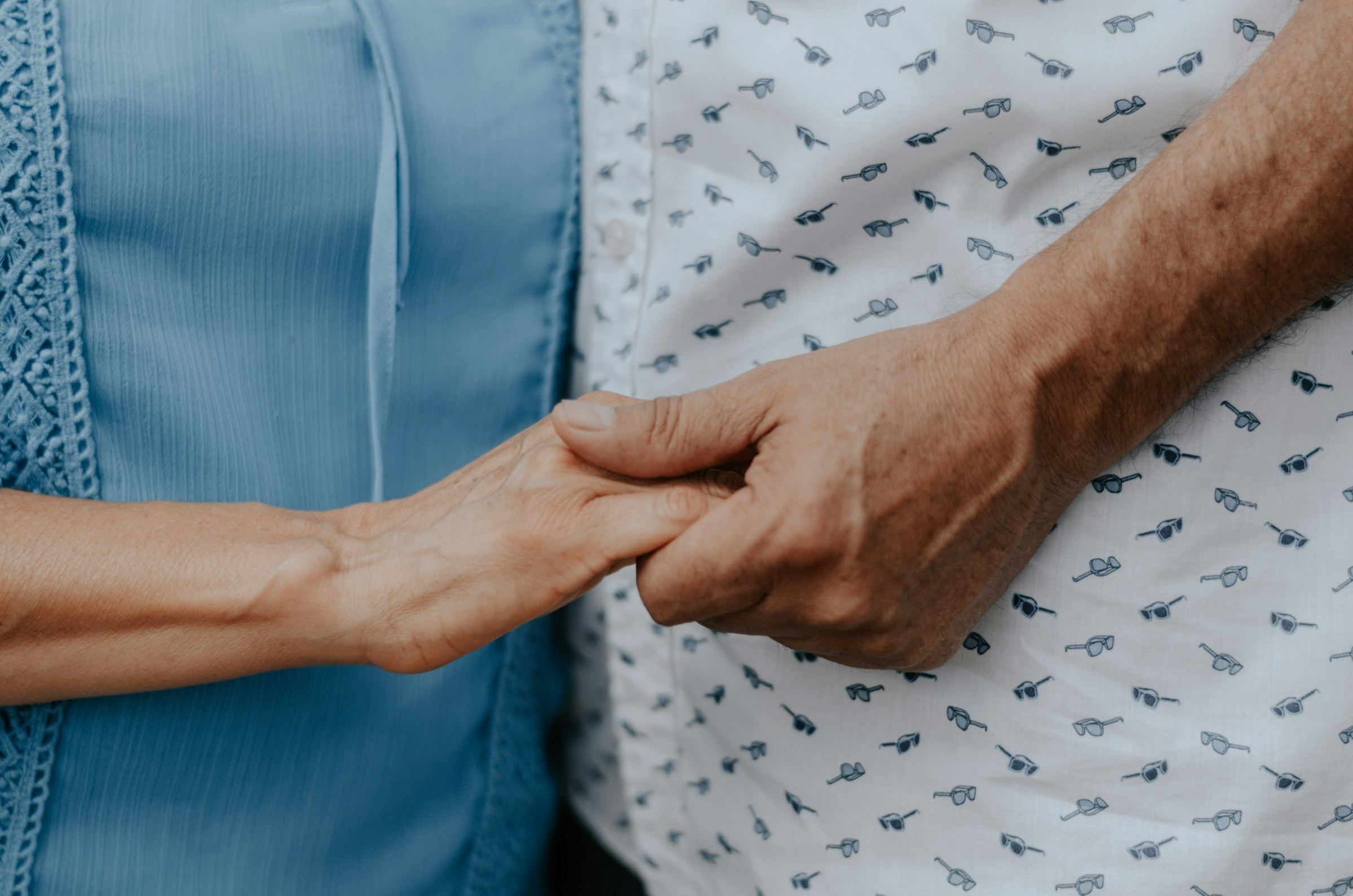 A caregiver holding an elderly person's hand
